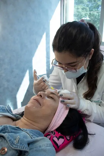 Dra. Maria Eduarda aplicando toxina botulínica (botox) em cliente, realizando um procedimento estético para suavizar rugas e linhas de expressão